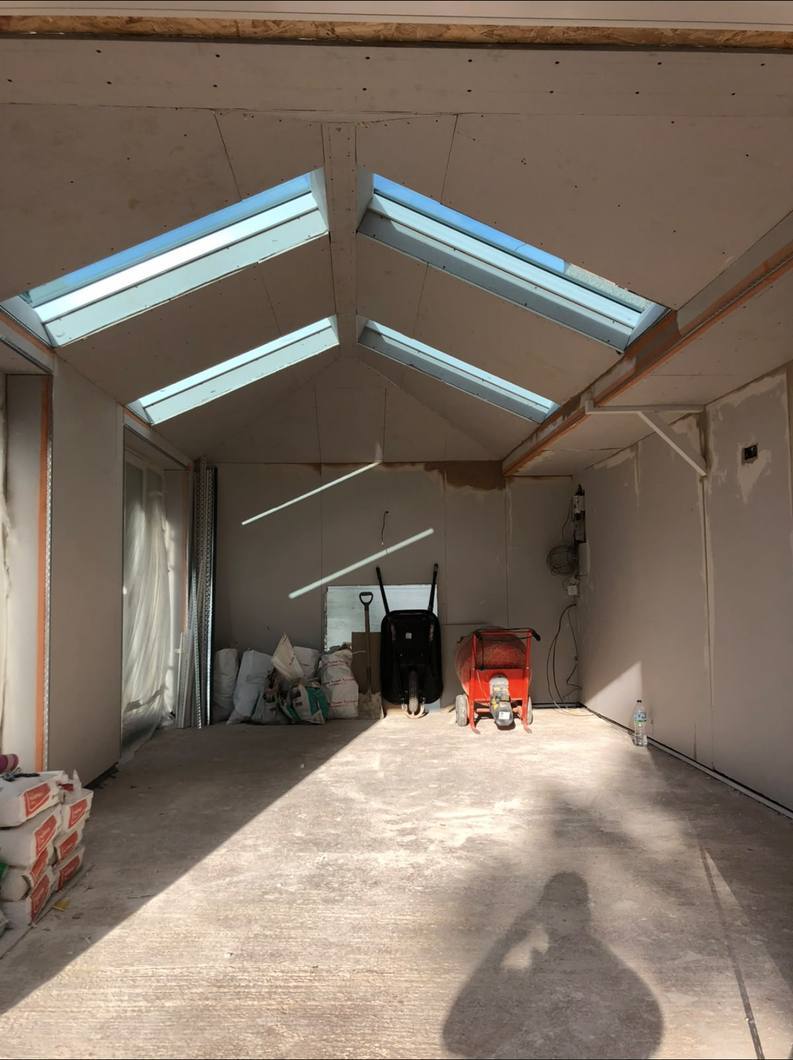 Pitched roof boarded out with skylights either side, ready for skimming