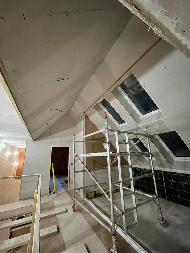 Loft conversion with sloped ceilings and skylights boarded, scaffold tower up